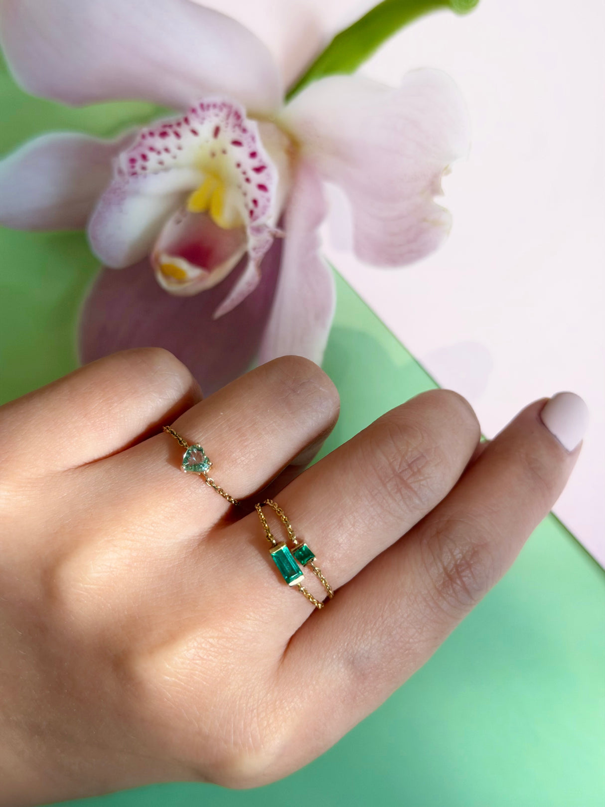 Emerald chain ring worn in a ring stack on a model’s hanf