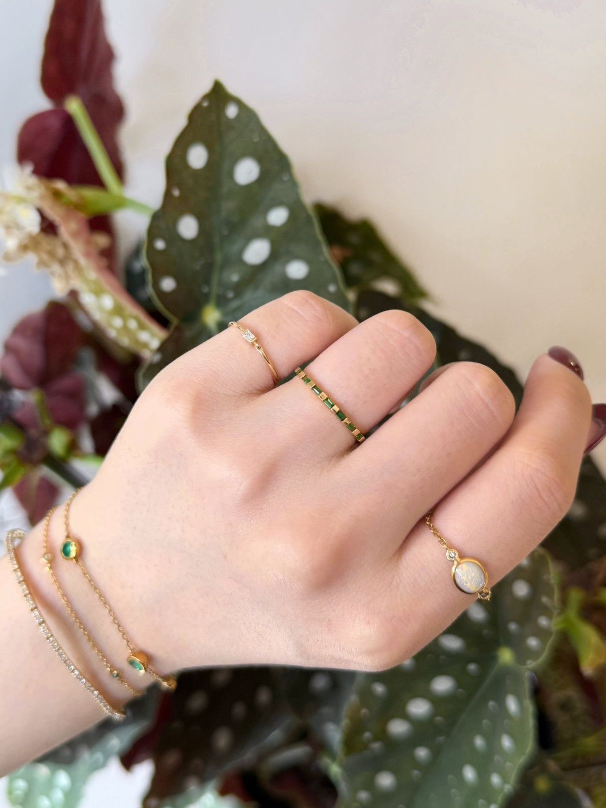 Tsavorite eternity wedding band in 18k Worn in a ring stack against a floral background