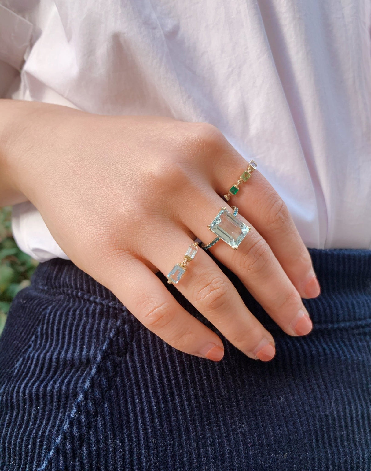 An 18K gold ring with a large emerald-cut aquamarine centerpiece and smaller blue diamond accents along the band. Perfect engagement ring or wedding ring in 18k gold.