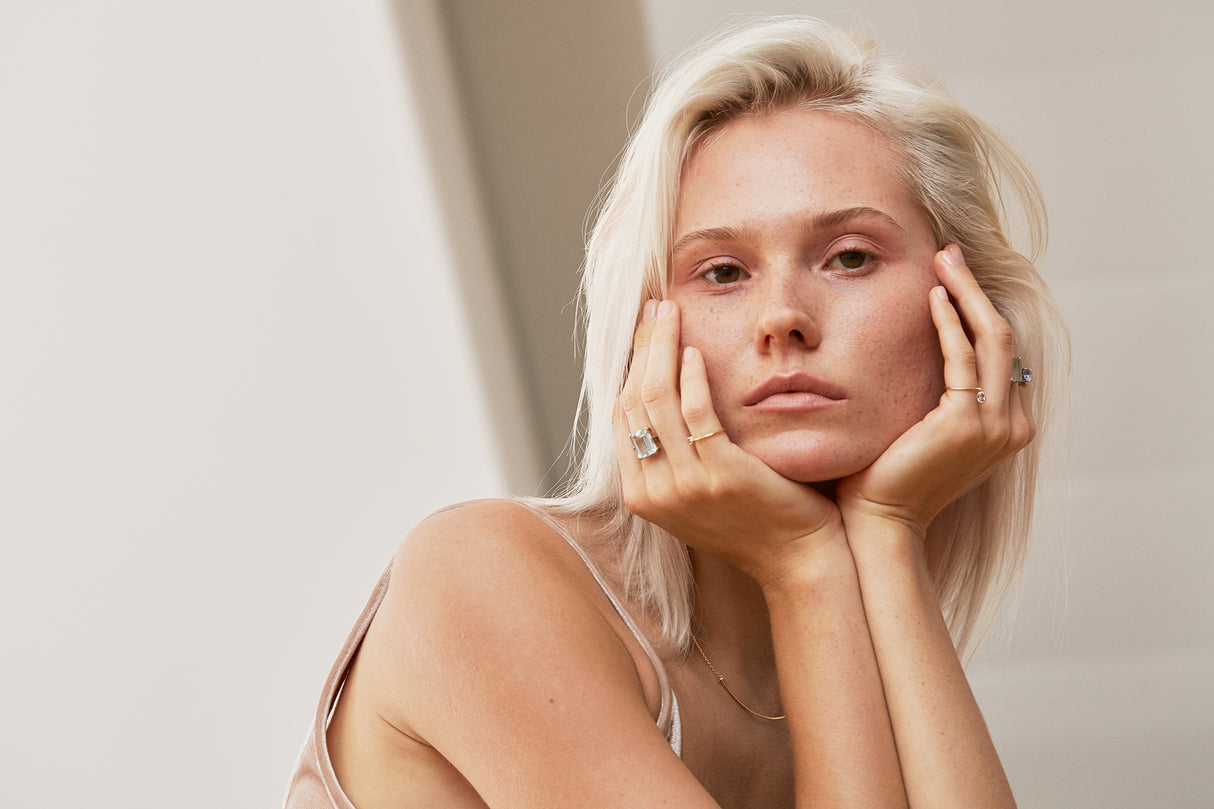 An 18K gold ring with a large emerald-cut aquamarine centerpiece and smaller blue diamond accents along the band. Perfect engagement ring or wedding ring in 18k gold.
