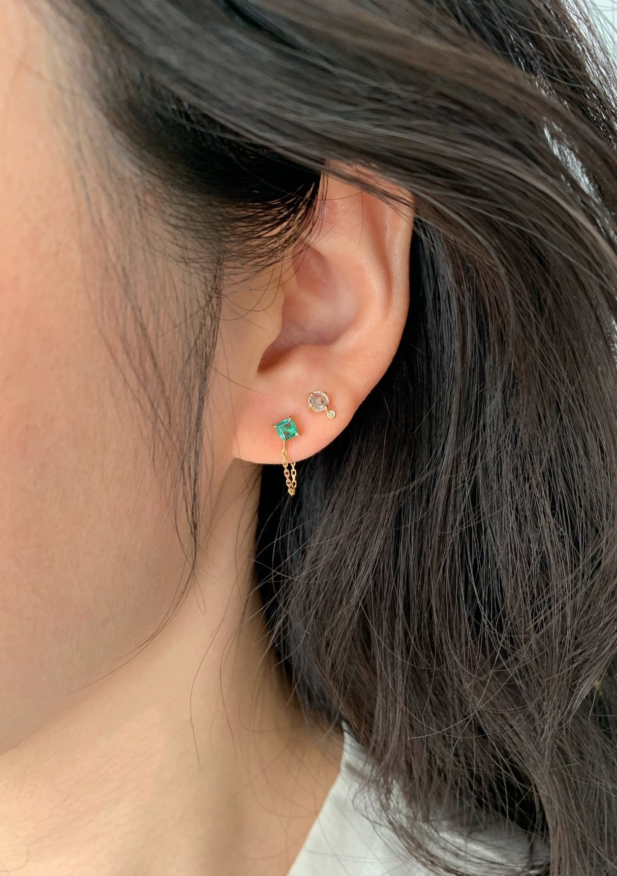 14k gold chain earring with a bright emerald gemstone on model
