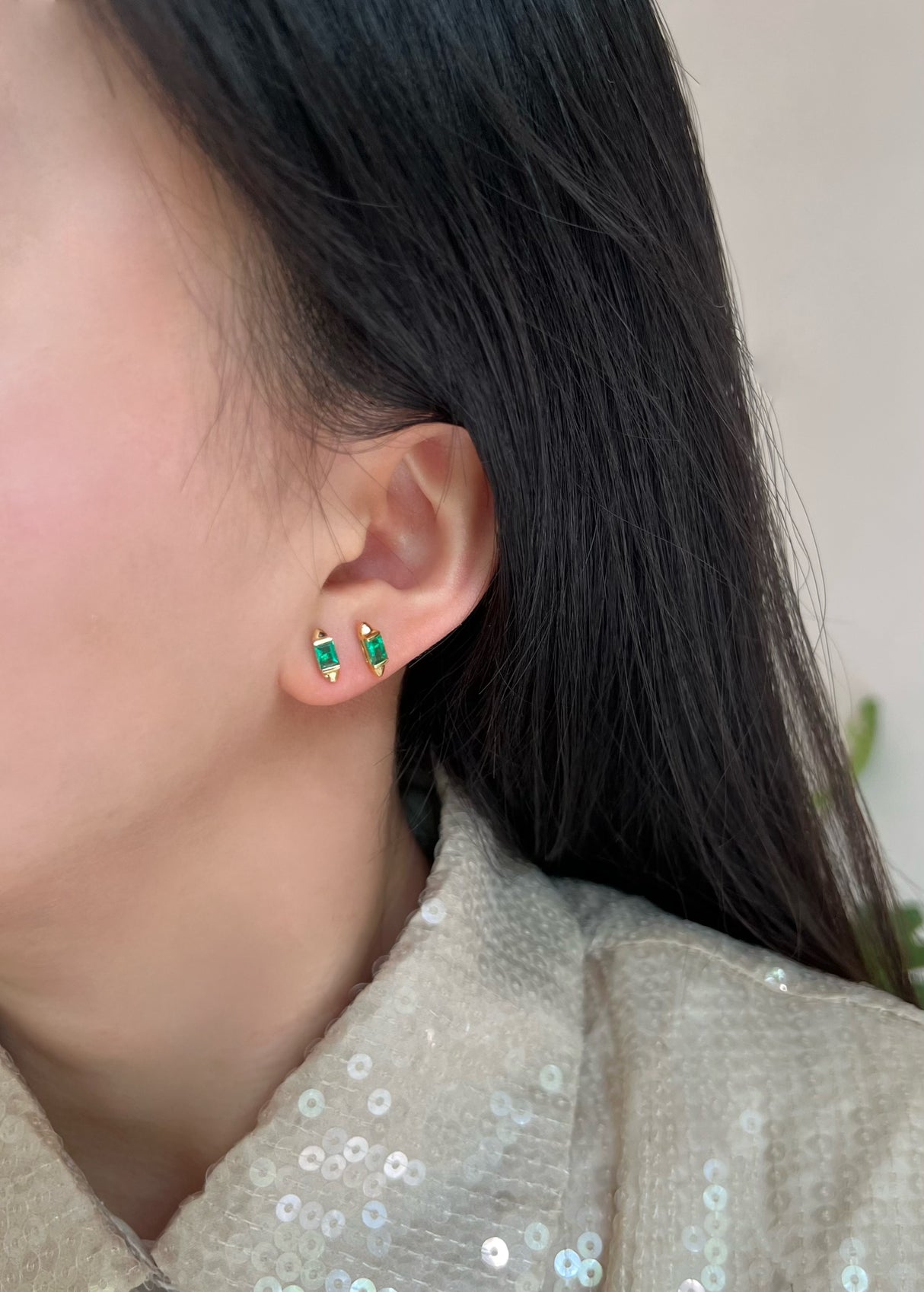18k gold emerald earrings with spike design in an ear stack worn on model.