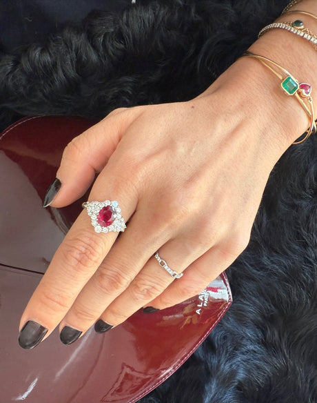 Hand wearing a ring with a red gemstone on a dark fur background