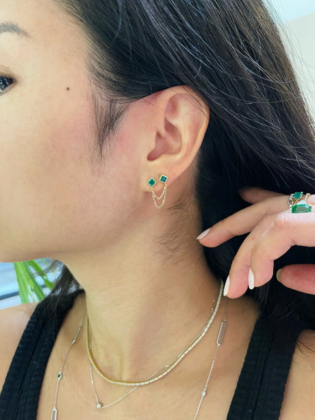 Emerald chain earring in 18k gold worn on model in an earring stack.
