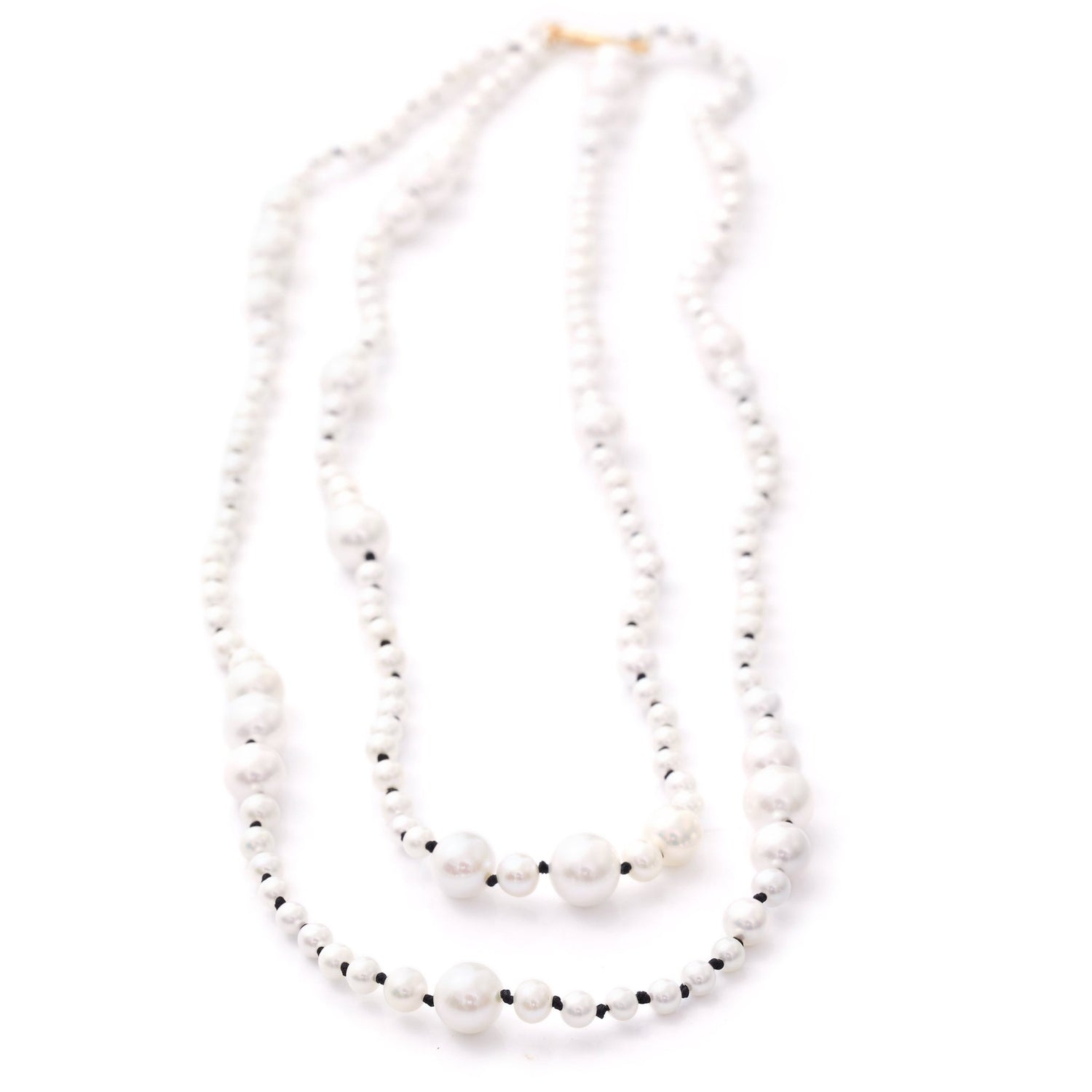 A two-strand akoya pearl necklace with a gold clasp, displaying the luster of the pearls and the reflective quality of the beads.