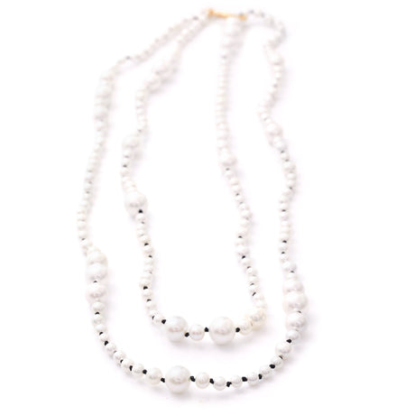 A two-strand akoya pearl necklace with a gold clasp, displaying the luster of the pearls and the reflective quality of the beads.