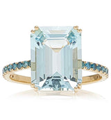 An 18K gold ring with a large emerald-cut aquamarine centerpiece and smaller blue diamond accents along the band.