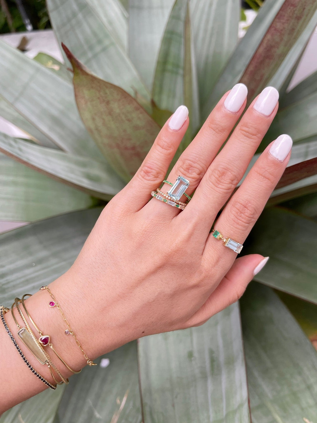 An 18K gold ring with a central aquamarine gem flanked by vivid green emerald gems on the sides. Handmade by female artisans with sustainably mined gemstones. The perfect Engagement ring or wedding ring
