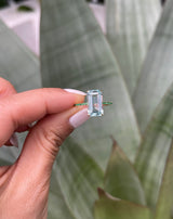 An 18K gold ring with a central aquamarine gem flanked by vivid green emerald gems on the sides. Handmade by female artisans with sustainably mined gemstones. Exquisite and modern in design. Perfect engagement ring or wedding ring.