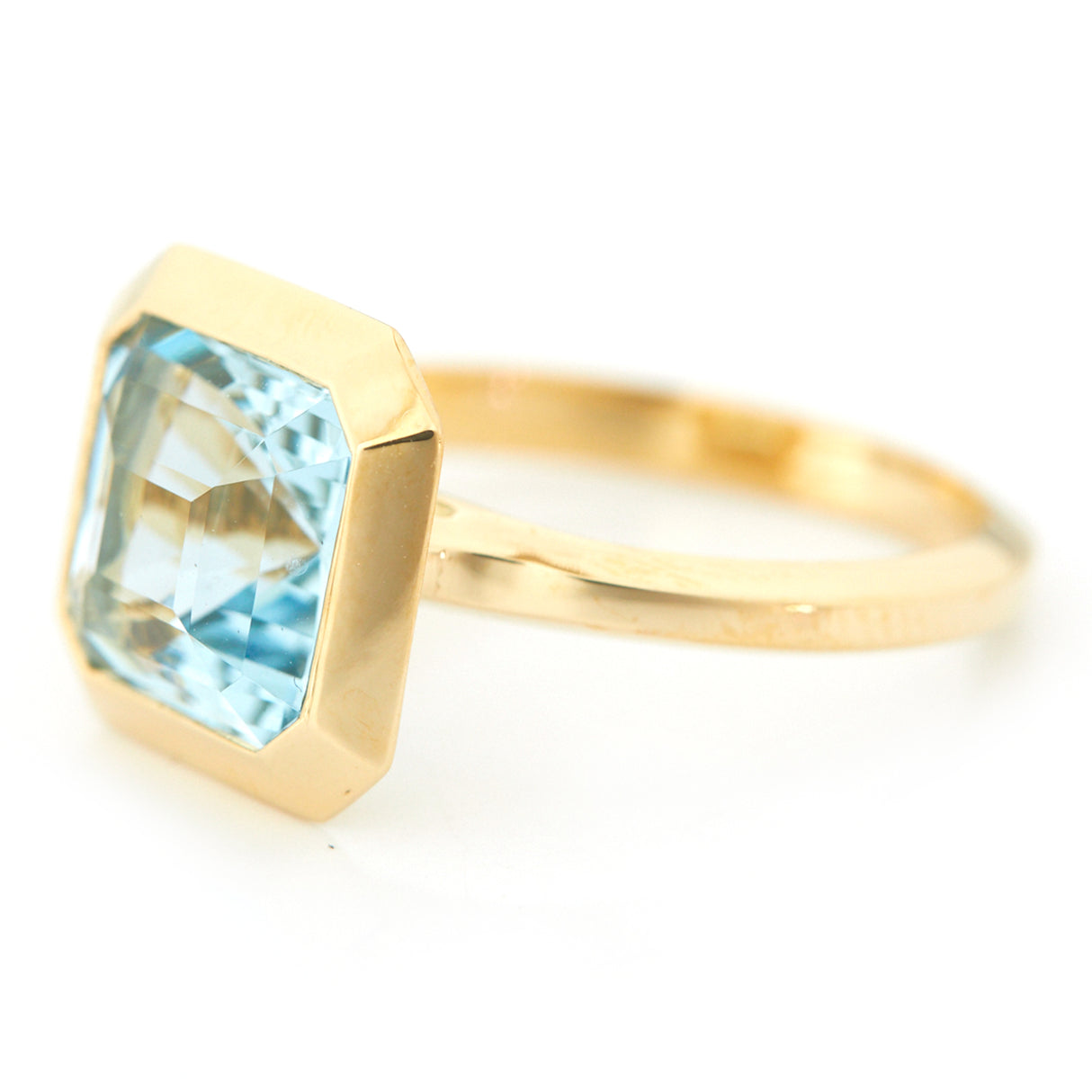 An 18k gold ring with a bezel set dazzling aquamarine gemstone. Hand cut aquamarine from Madagascar handmade by female artisans into an incredible everyday heirloom. 