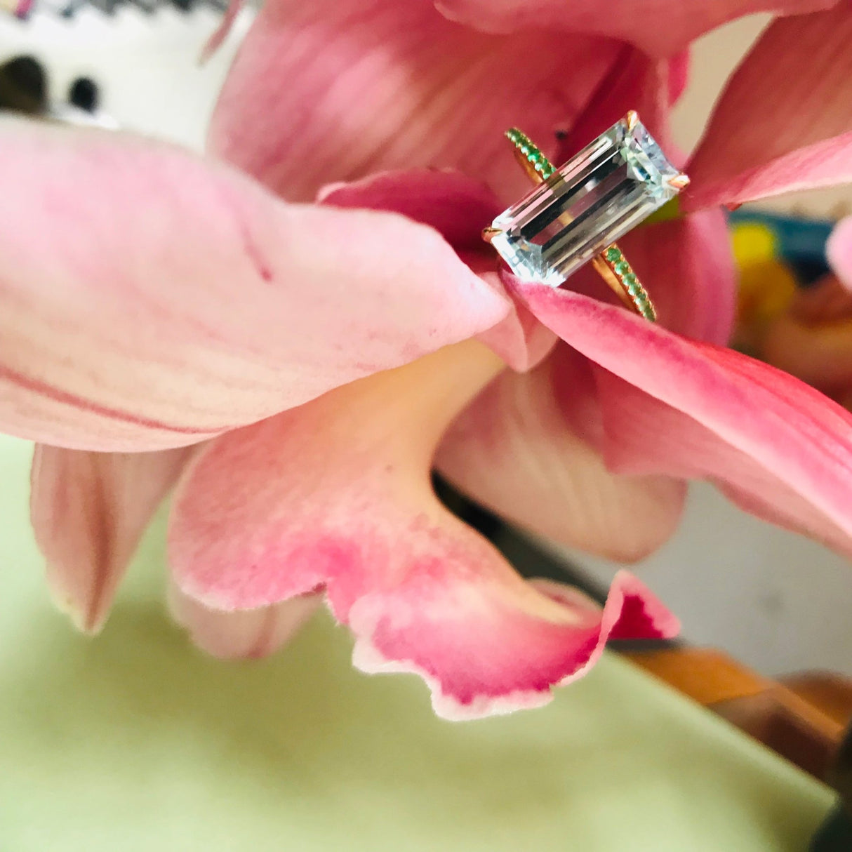 An 18K gold ring with a central aquamarine gem flanked by vivid green emerald gems on the sides. Handmade by female artisans with sustainably mined gemstones. Exquisite and modern in design. 