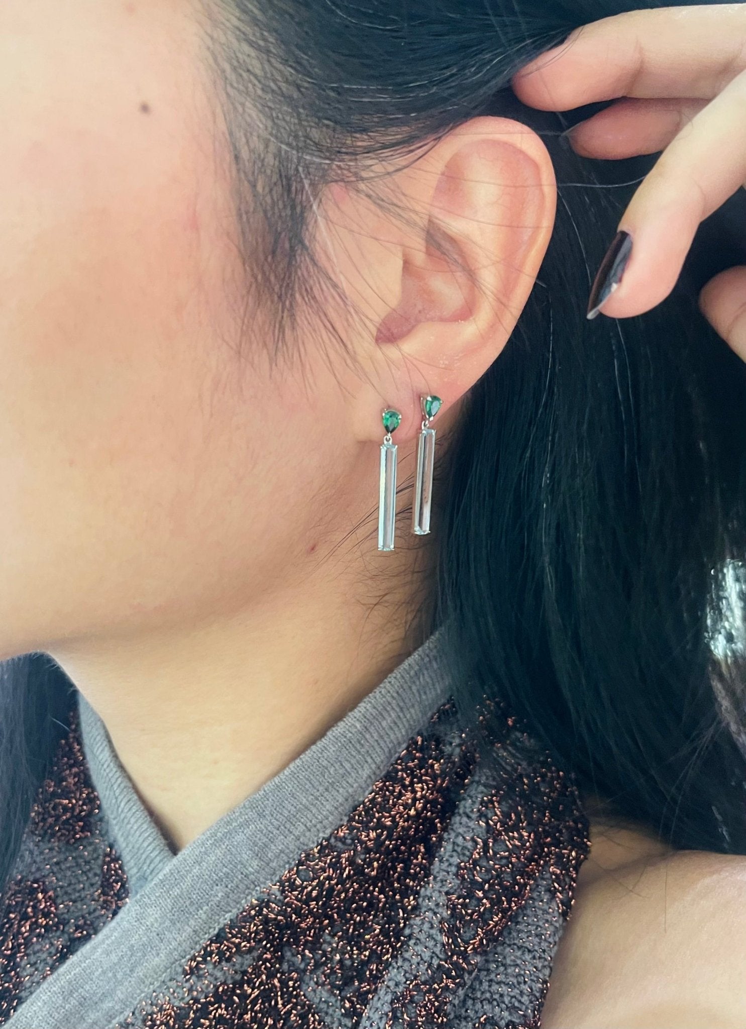 A pair of linear bar earrings featuring top green tsavorite and bottom clear aquamarine gemstones, set in platinum mounting. Handmade by female artisans with sustainably mined gemstones. 