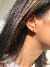 gold Huggies with blue sapphires in 14k on a model’s earring stack