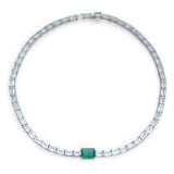 A necklace featuring a series of linked gemstones, with larger emerald cuts at the center and smaller aquamarine cuts on the sides, handmade by female artisans. Ethically sourced gemstones made into colorful wearable art. 