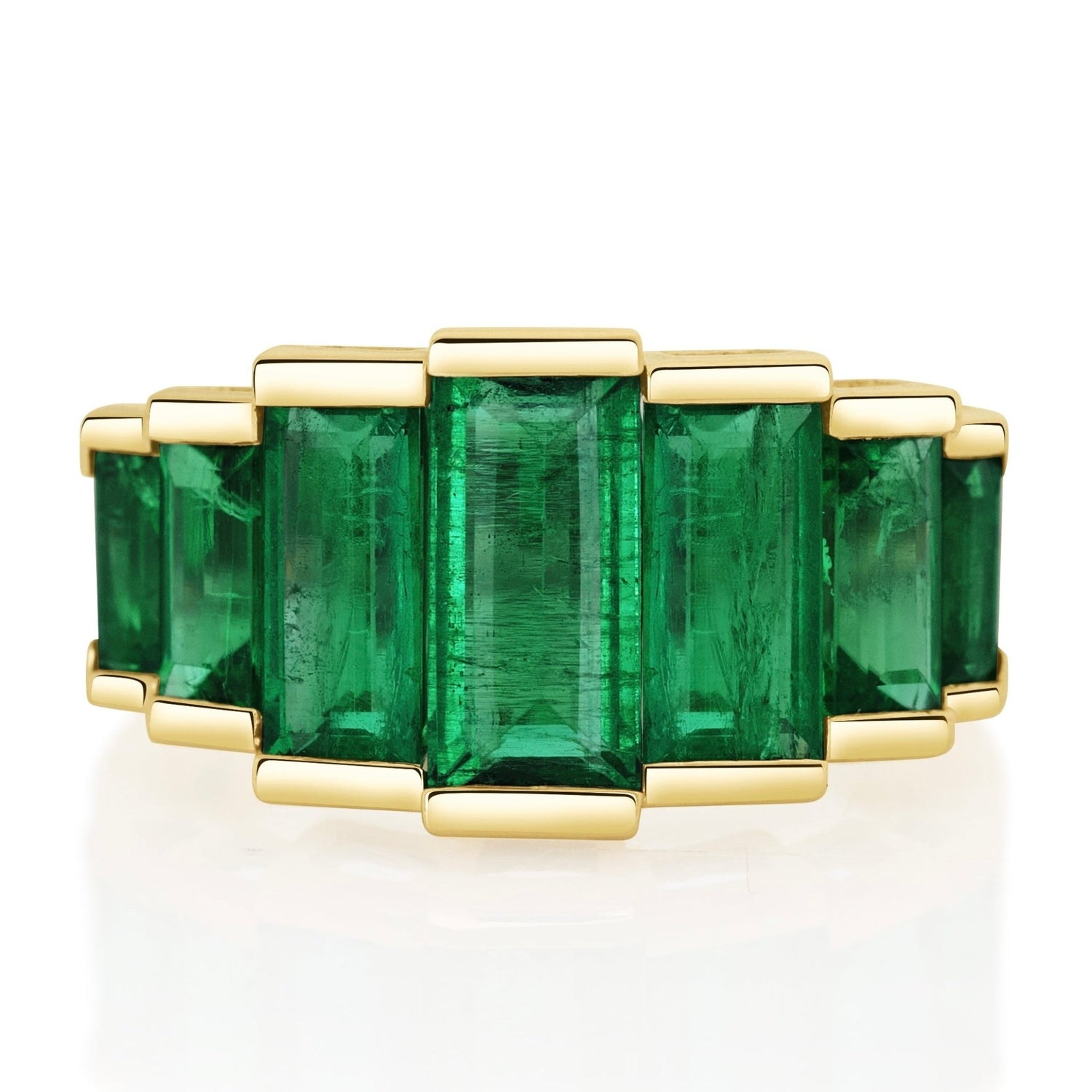 Gold ring with seven emerald green gemstones on a white background