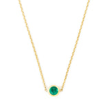 Gold necklace with a green gemstone on a white background