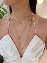Person wearing a white top with thin straps and multiple gold zodiac necklaces.
