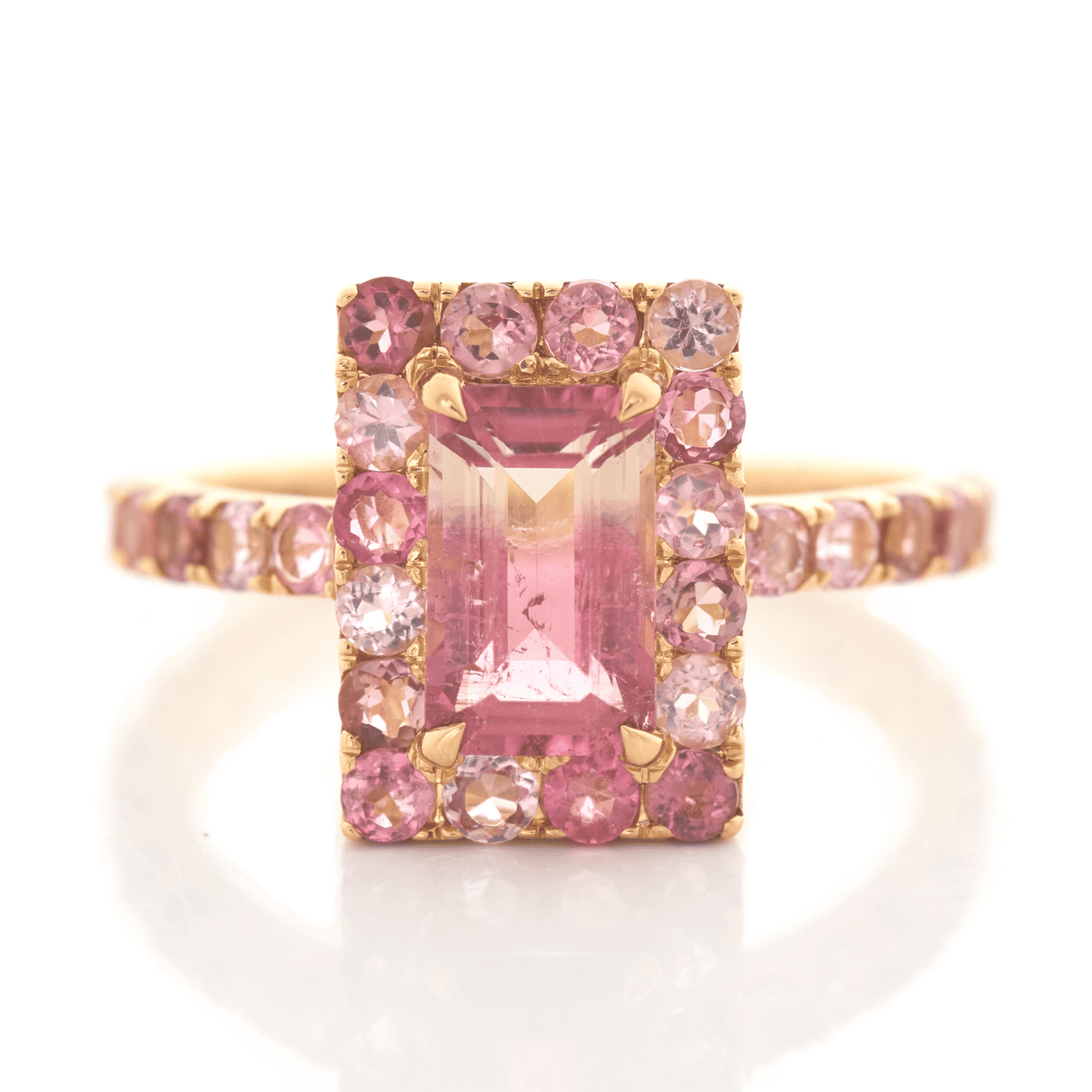 An ombré pink Tourmaline ring with a central, rectangular pink tourmaline surrounded by smaller pink tourmalines set in a gold band.