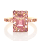 An ombré pink Tourmaline ring with a central, rectangular pink tourmaline surrounded by smaller pink tourmalines set in a gold band.