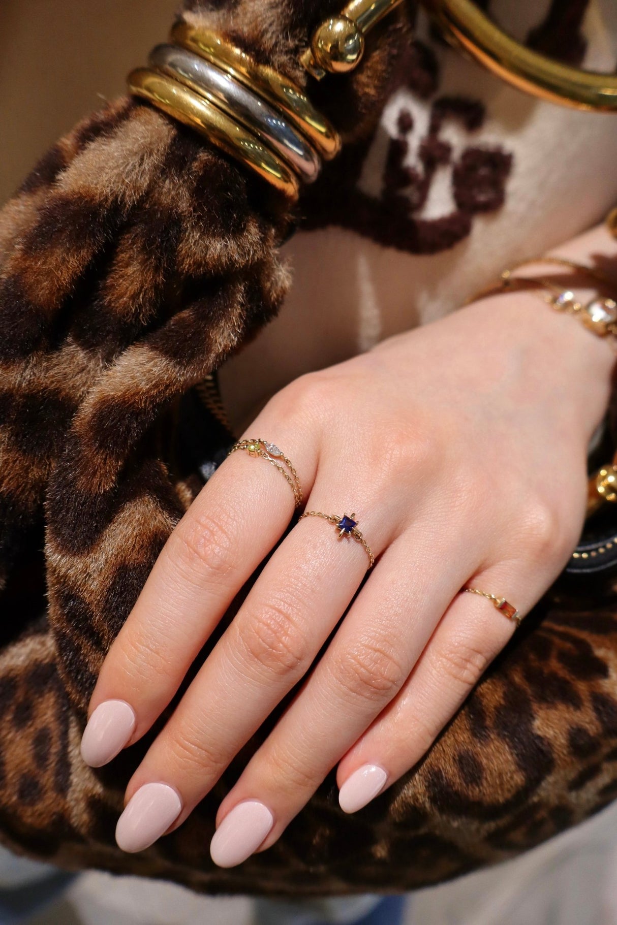 Hand with multiple rings on a leopard print background