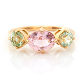 An 18k yellow gold ring with a central pink tourmaline and two mint green tourmaline stones on either side, set against a white background.