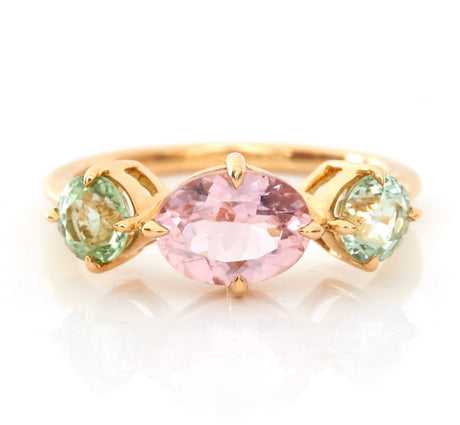 An 18k yellow gold ring with a central pink tourmaline and two mint green tourmaline stones on either side, set against a white background.