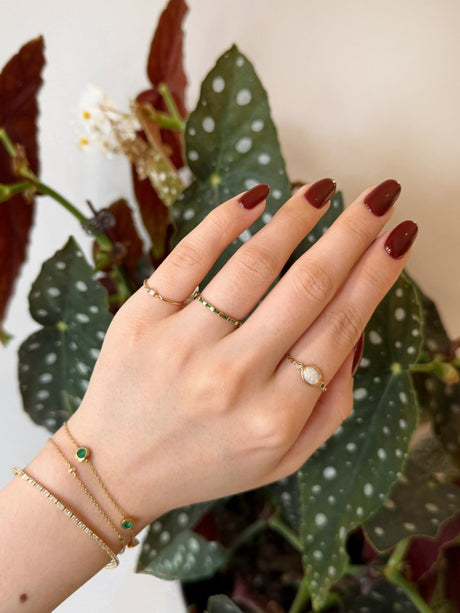 Tsavorite eternity wedding band in 18k Worn in a ring stack against a floral background