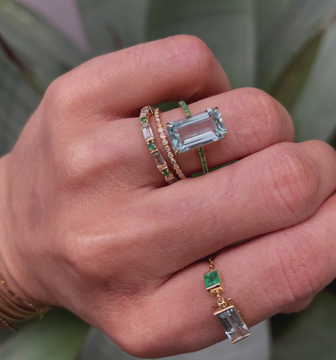 An 18K gold ring with a central aquamarine gem flanked by vivid green emerald gems on the sides. Handmade by female artisans with sustainably mined gemstones. Exquisite and modern in design. 
